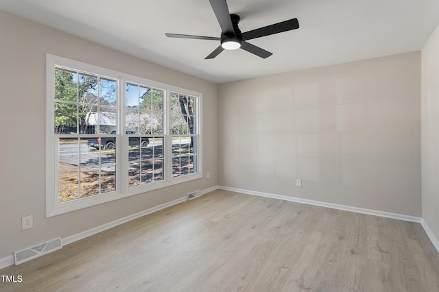 empty room featuring a ceiling fan, baseboards, visible vents, and light wood-type flooring