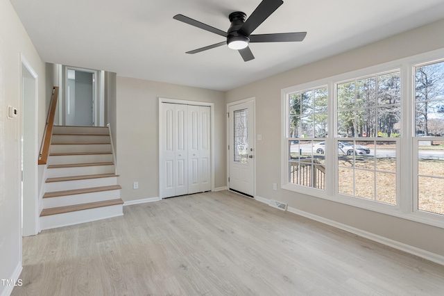 entryway featuring visible vents, wood finished floors, baseboards, ceiling fan, and stairway