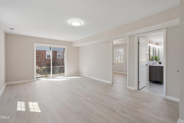 interior space featuring light wood-style floors, baseboards, and visible vents