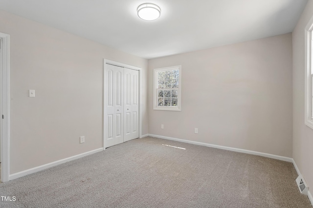 unfurnished bedroom featuring baseboards, visible vents, carpet, and a closet