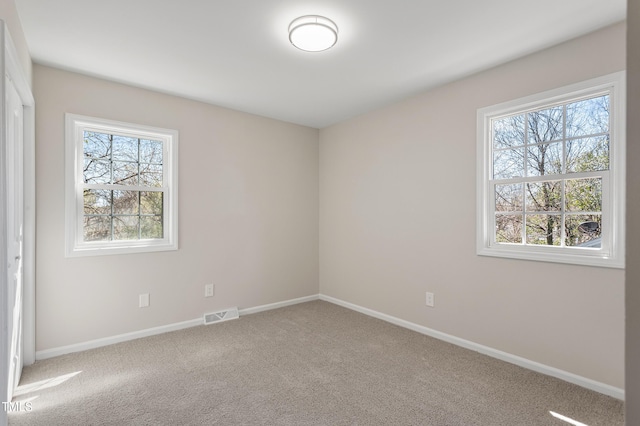 spare room featuring carpet flooring, baseboards, and visible vents