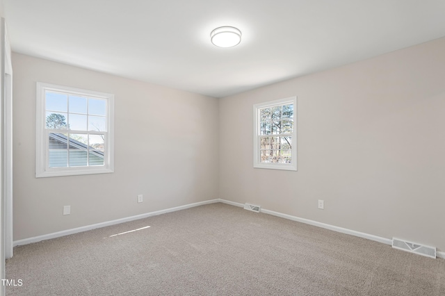 spare room with carpet flooring, baseboards, and visible vents