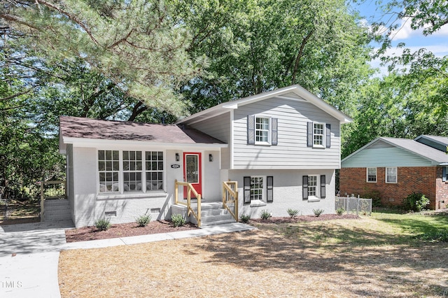 split level home with fence and brick siding