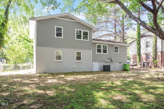 back of house with a lawn, crawl space, central AC, and fence