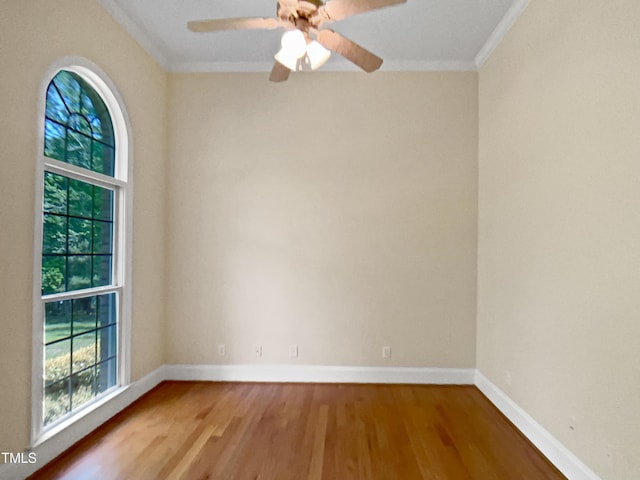 spare room featuring baseboards, ornamental molding, a ceiling fan, and wood finished floors