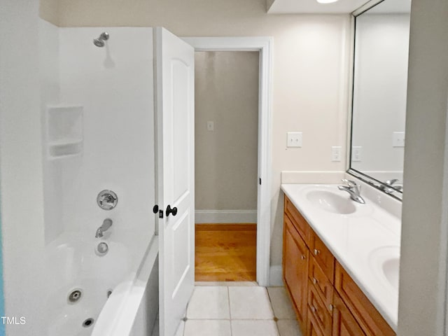 full bath with tile patterned flooring, double vanity, shower / bathtub combination, baseboards, and a sink