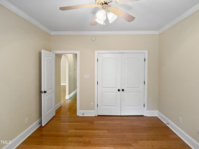 unfurnished bedroom featuring crown molding, a closet, baseboards, and light wood-type flooring