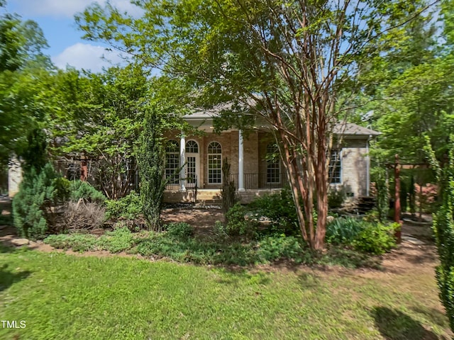 obstructed view of property featuring covered porch, brick siding, and a front yard