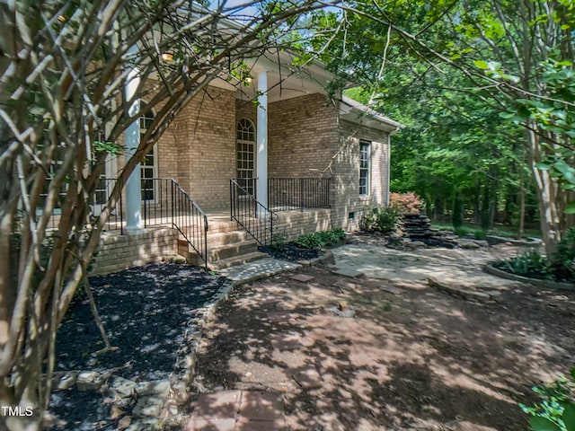 view of side of home with covered porch and brick siding
