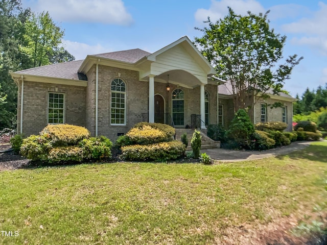 ranch-style house featuring brick siding, a front yard, and roof with shingles