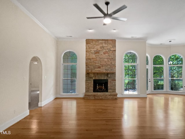unfurnished living room featuring ceiling fan, crown molding, a fireplace, wood finished floors, and baseboards