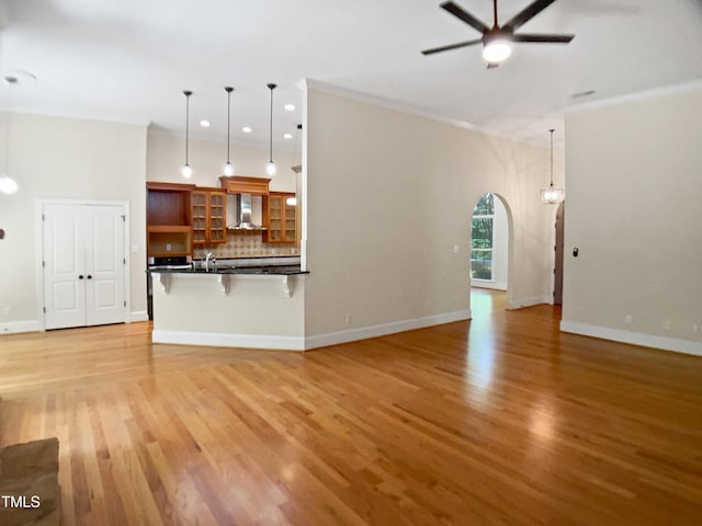 unfurnished living room with arched walkways, ceiling fan, recessed lighting, and light wood-style flooring