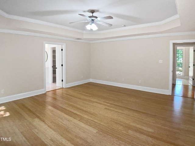 unfurnished room with a ceiling fan, wood finished floors, and a tray ceiling