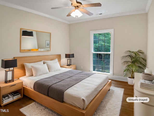 bedroom with baseboards, ornamental molding, wood finished floors, and visible vents