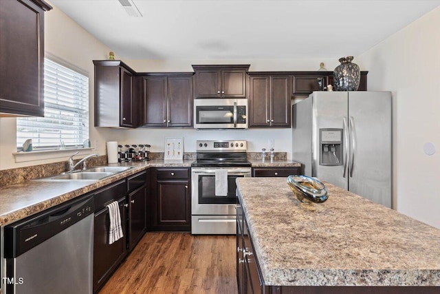 3912 Huntsmoor Ln, Wilson, NC 27896 - kitchen with dark brown cabinetry, appliances with stainless steel finishes, a sink, a kitchen island, and dark wood-style floors