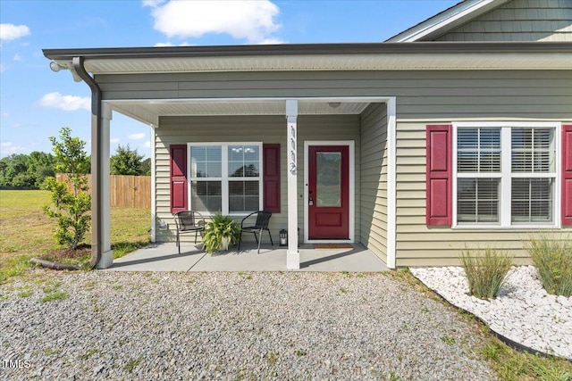 view of exterior entry with fence and covered porch