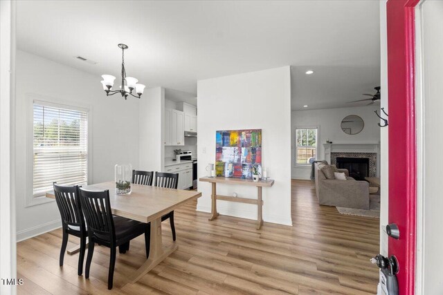 dining area with light wood finished floors, plenty of natural light, a chandelier, a ceiling fan, and recessed lighting