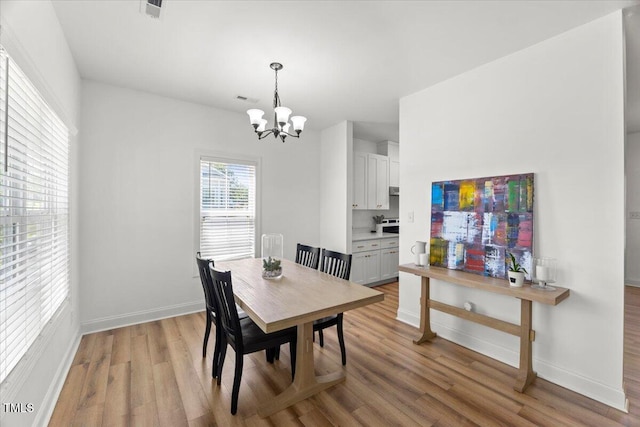 dining room featuring a chandelier, light wood-style floors, and baseboards