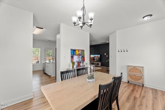 dining room with a chandelier, light wood-style flooring, and baseboards