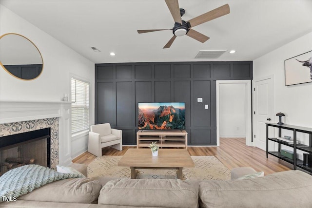 living room with a ceiling fan, light wood finished floors, a fireplace, recessed lighting, and baseboards