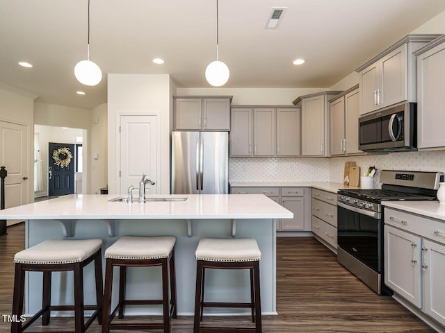 555 Whitley Ridge Dr, Clayton, NC 27527 - kitchen with stainless steel appliances, gray cabinets, a sink, a kitchen bar, and recessed lighting
