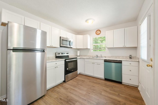 145 Mark St, Franklinton, NC 27525 - kitchen featuring light wood-type flooring, white cabinetry, a textured ceiling, a sink, and appliances with stainless steel finishes