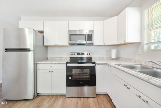 145 Mark St, Franklinton, NC 27525 - kitchen with light countertops, white cabinetry, a sink, light wood-style flooring, and stainless steel appliances