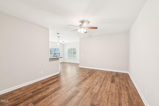 spare room with a ceiling fan, wood finished floors, and baseboards