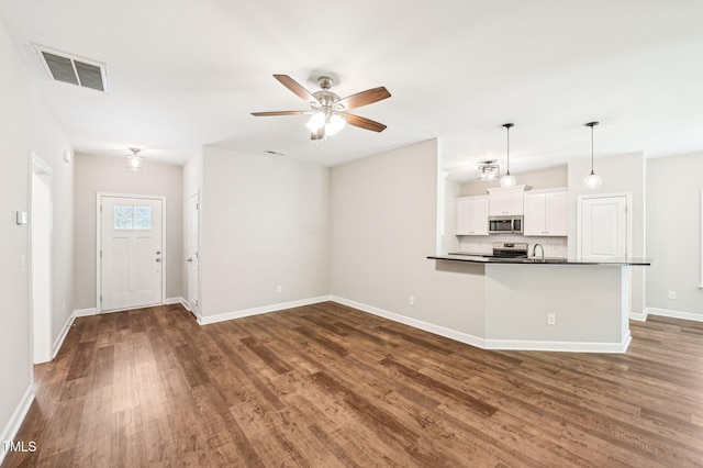unfurnished living room with dark wood-type flooring, baseboards, a ceiling fan, and a sink