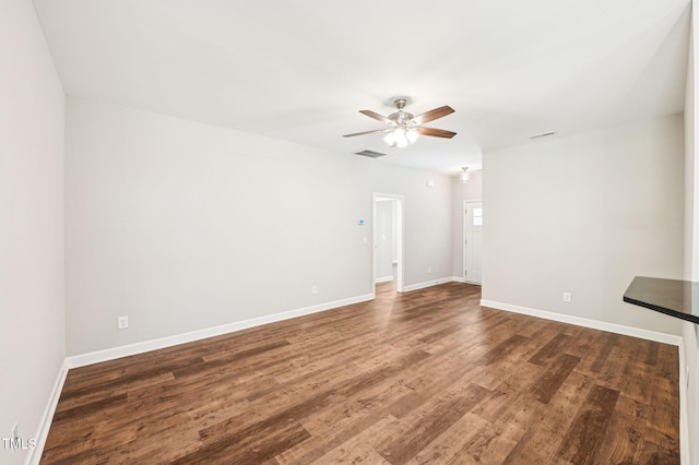 empty room with a ceiling fan, dark wood-style flooring, and baseboards