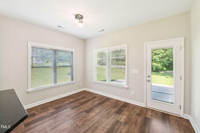 unfurnished dining area featuring plenty of natural light, dark wood finished floors, and baseboards