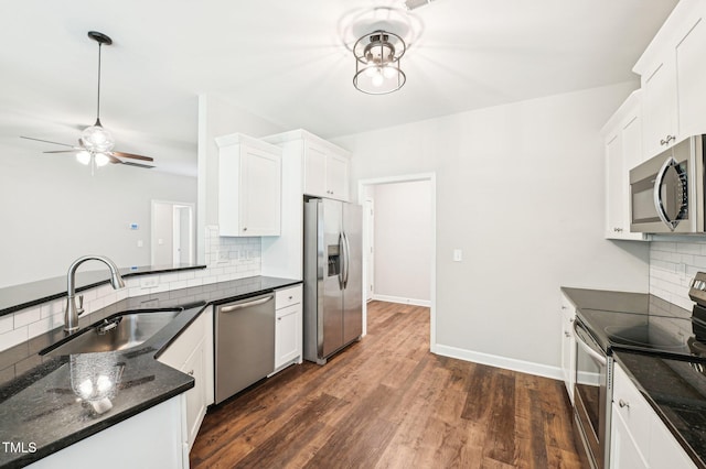kitchen featuring appliances with stainless steel finishes, a sink, decorative backsplash, a ceiling fan, and white cabinets