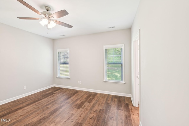 unfurnished room featuring plenty of natural light, dark wood finished floors, baseboards, and ceiling fan