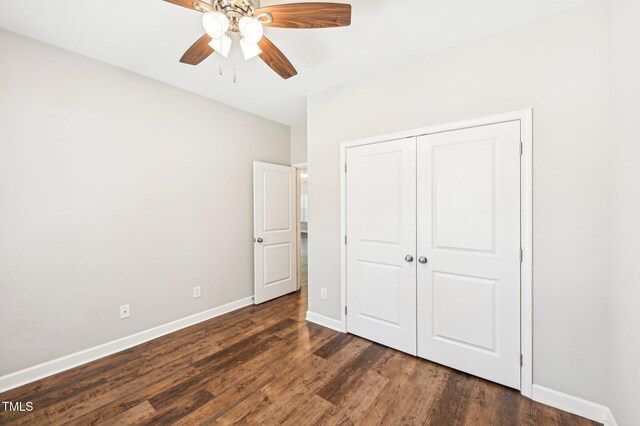 unfurnished bedroom featuring dark wood-style floors, baseboards, a closet, and ceiling fan