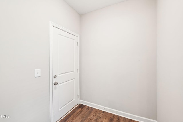 doorway with dark wood-type flooring and baseboards