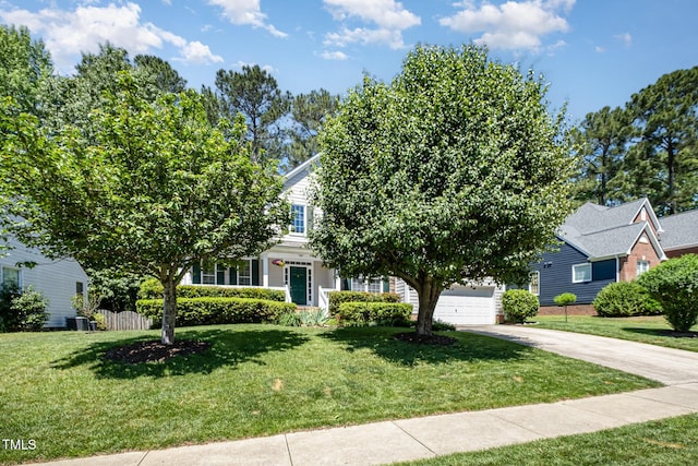 view of property hidden behind natural elements featuring concrete driveway and a front yard