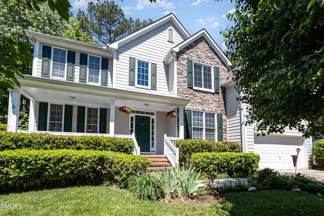 view of front facade with driveway, a porch, and stone siding