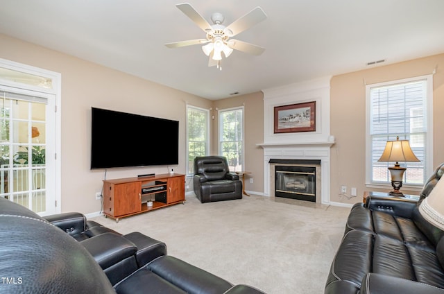 living room featuring ceiling fan, baseboards, light carpet, and a fireplace