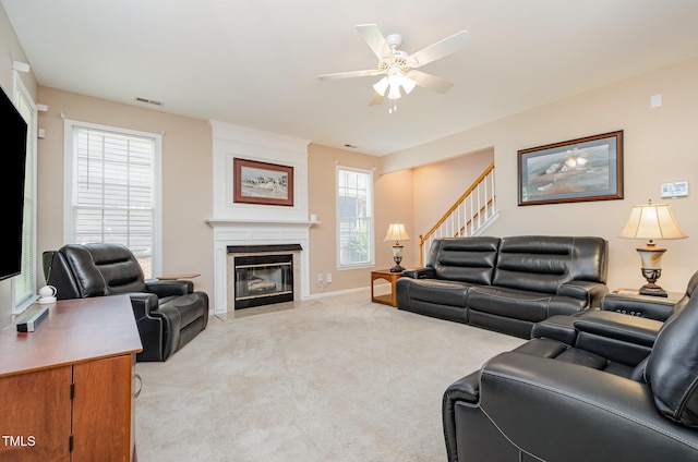 living area with a ceiling fan, light carpet, stairway, a fireplace, and baseboards