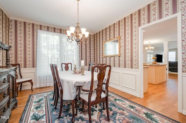 dining area with a chandelier, a wainscoted wall, ornamental molding, light wood-style flooring, and wallpapered walls
