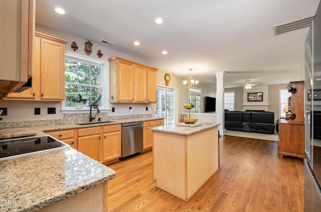 kitchen with stainless steel dishwasher, a sink, light brown cabinets, a kitchen island, and a fireplace