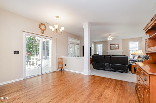 living area with light wood-style flooring, baseboards, a chandelier, ceiling fan, and a fireplace
