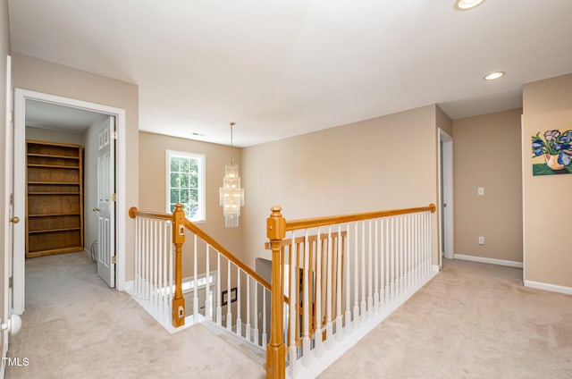hallway with an upstairs landing, carpet, baseboards, recessed lighting, and a chandelier