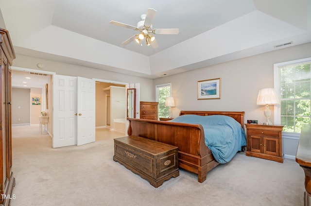 bedroom with light colored carpet, baseboards, a tray ceiling, and ceiling fan
