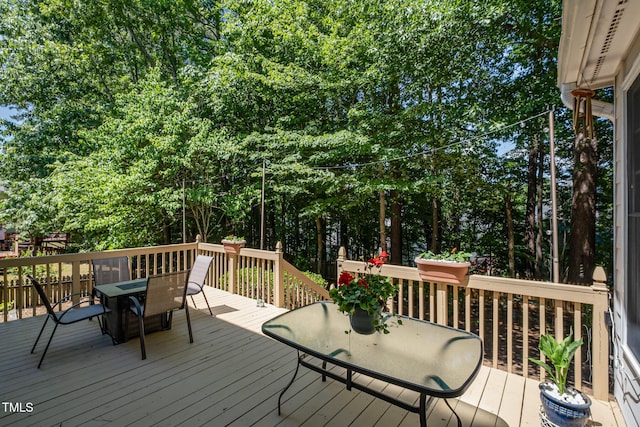 wooden terrace with outdoor dining space and view of scattered trees