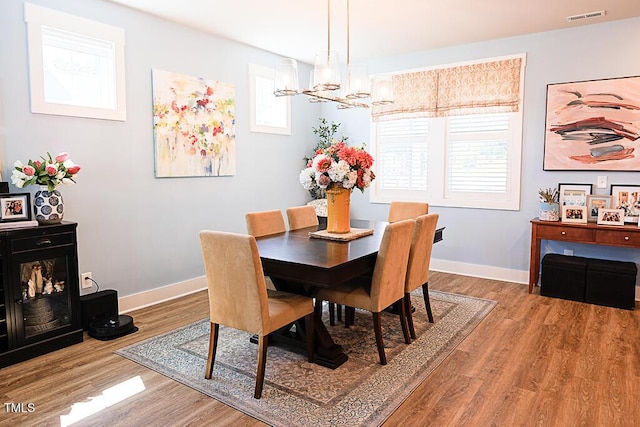 dining room with a chandelier, baseboards, visible vents, and wood finished floors
