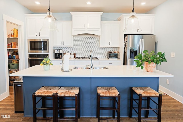 kitchen featuring a sink, appliances with stainless steel finishes, a kitchen breakfast bar, and white cabinets