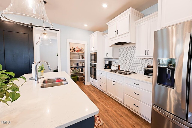 kitchen with a sink, appliances with stainless steel finishes, light wood finished floors, and light countertops