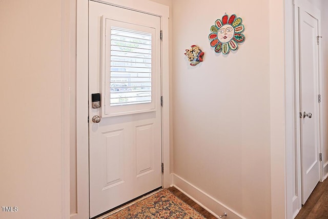 doorway featuring baseboards and dark wood finished floors
