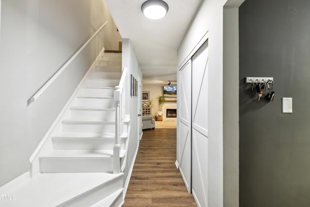 stairs with wood finished floors and a fireplace